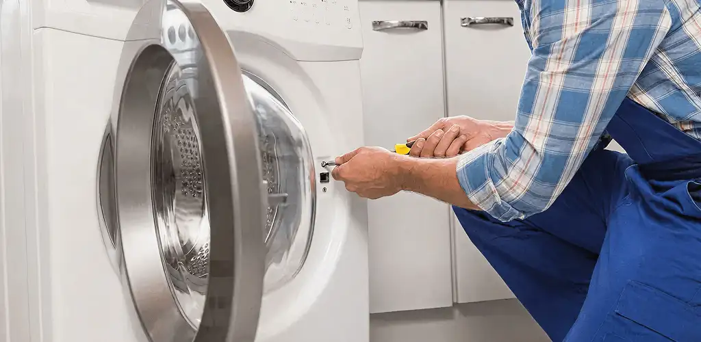 Handyman repairing a clothes dryer and checking electrical connections in Columbus, GA