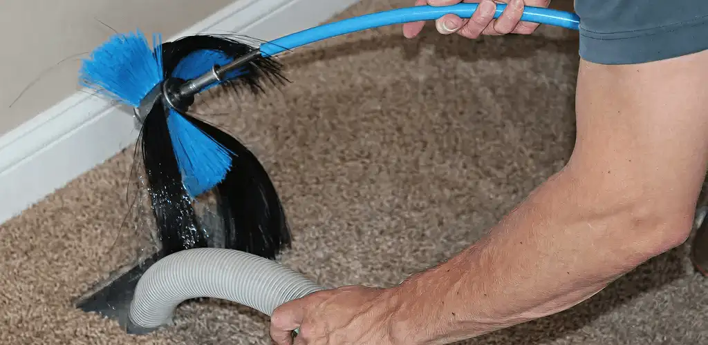 Dryer vent cleaning technician brushing lint from a vent line in Columbus, GA