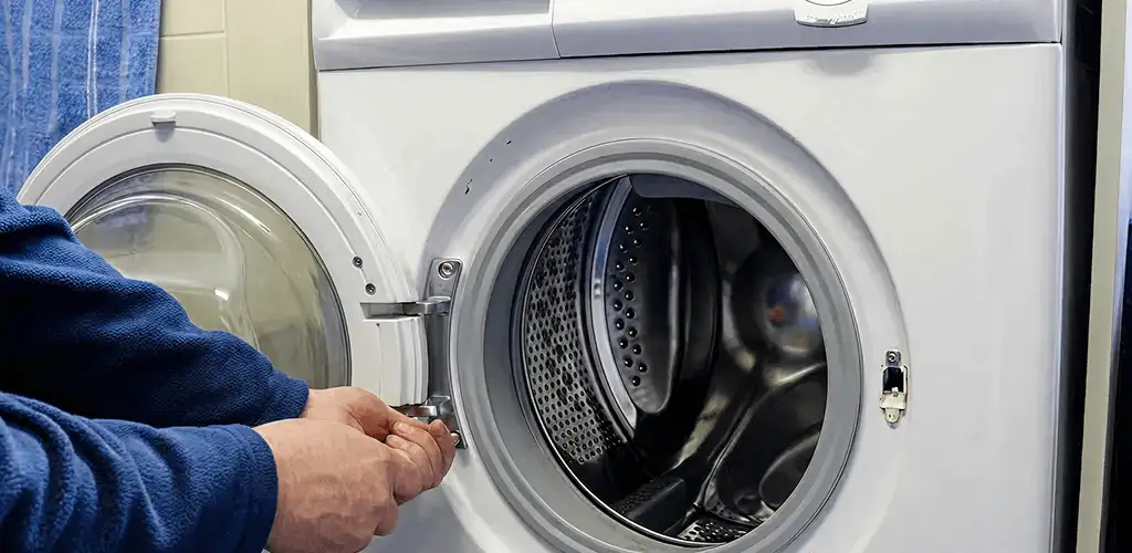 Washing machine repair handyman checking a front-load washer door and latch in Columbus, GA