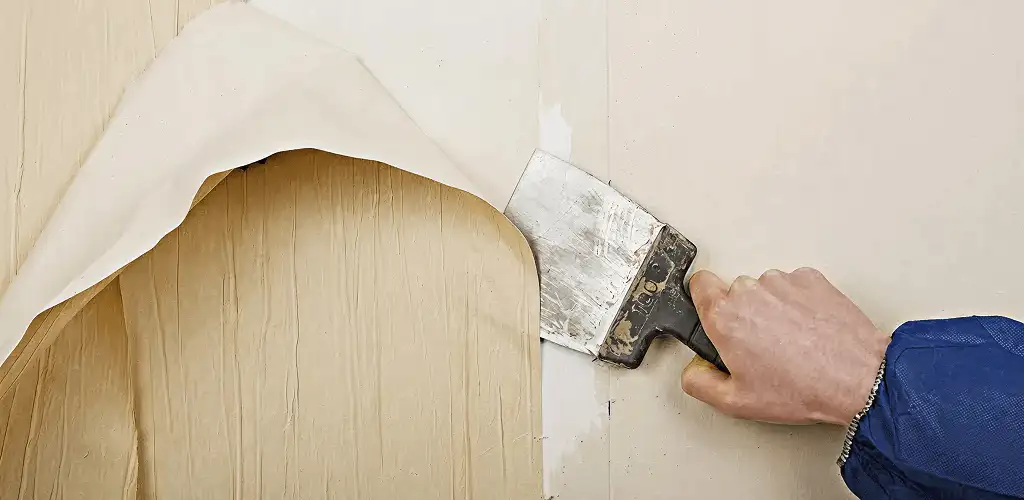 Handyman removing wallpaper with a scraper for wall preparation in Columbus, GA