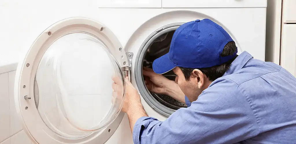 Washing machine repair handyman inspecting a front-load washer drum in Columbus, GA