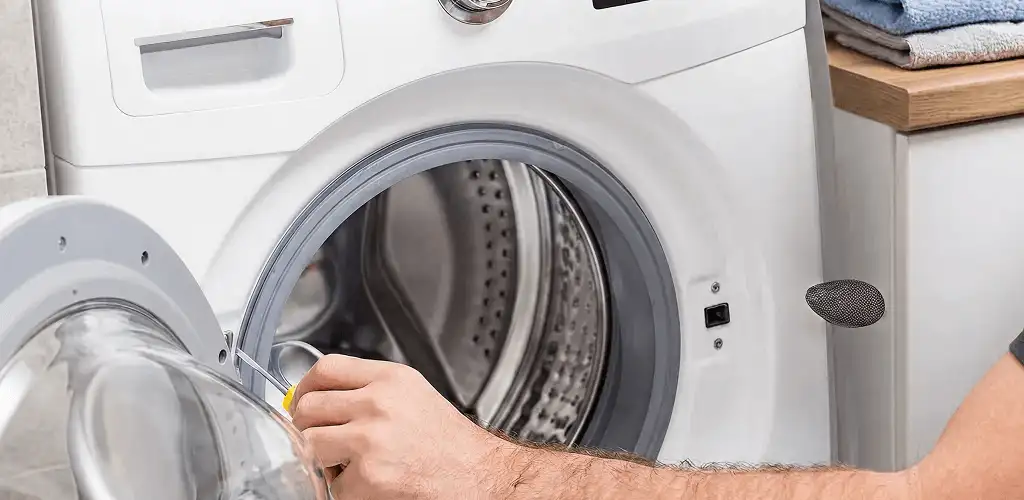 Handyman repairing a front-load washing machine and inspecting the drum in Columbus, GA
