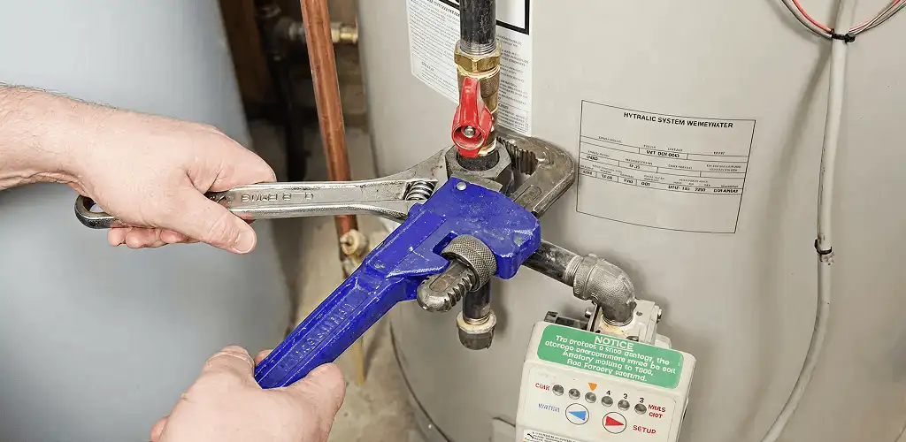 Water heater repair technician tightening the shutoff valve and supply line in Columbus, GA